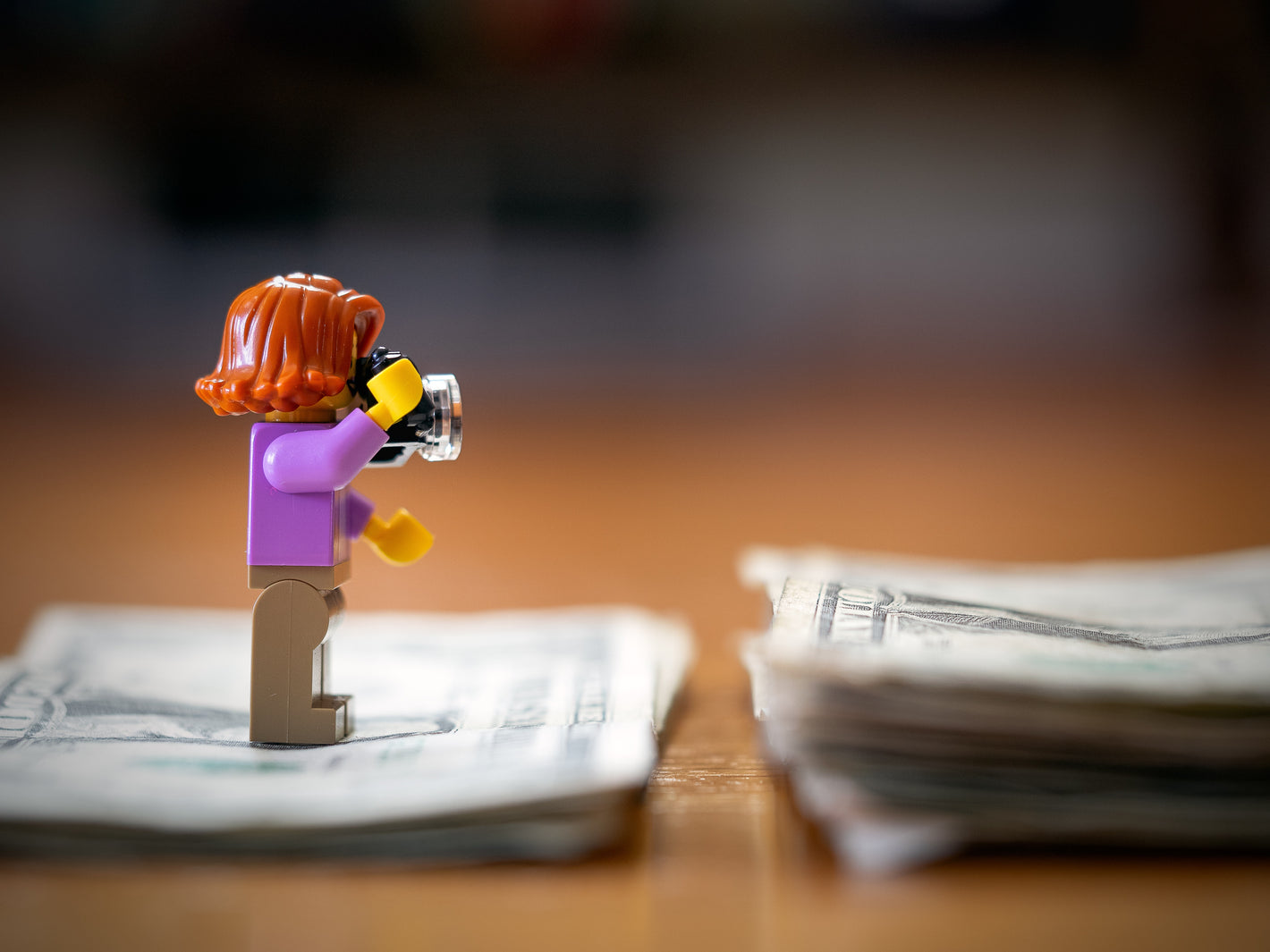 Small figurine holding a camera with money in the background